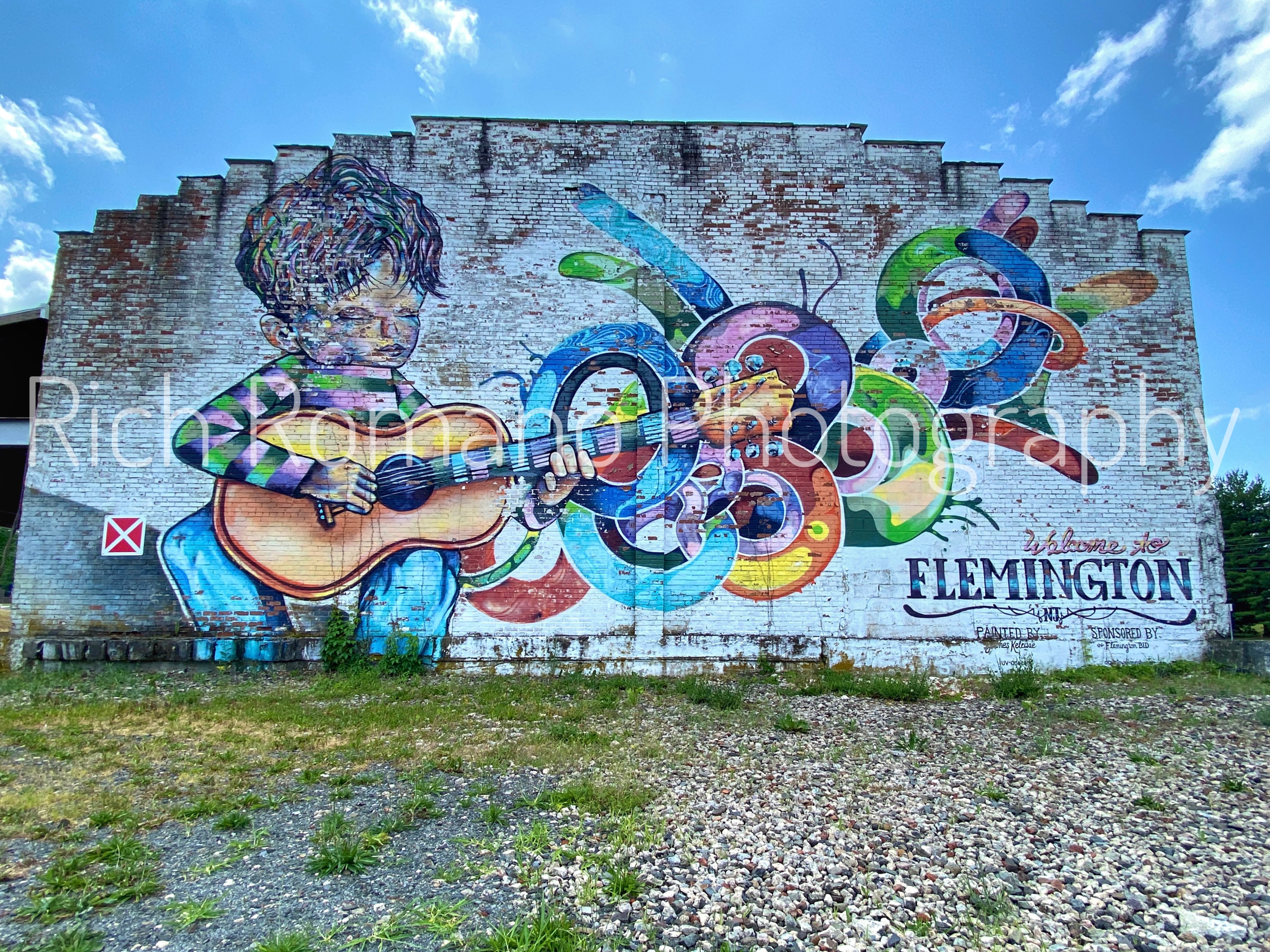 mural on white brick wall in flemington new jersey depicting a man playing a colorful guitar